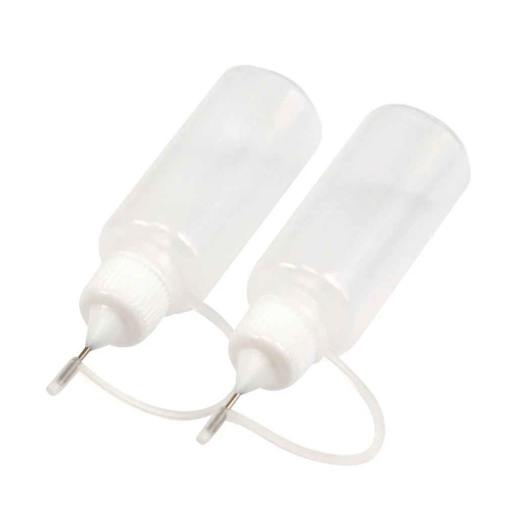 Two white plastic bottles with nozzles on a white background. Ideal for filling with glues or paints.