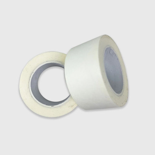 Two rolls of white removable low-tack tape on a light grey background