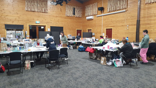 Crafters working on scrapbooking and paper crafts projects at individual tables during Handmade Craftery Retreat weekend