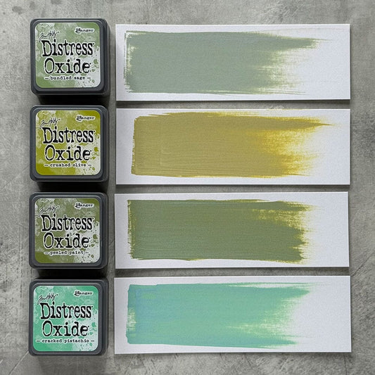 Four Ranger Distress Oxide ink pads from Kit 3 with swatched colours: Bundled Sage, Crushed Olive, Peeled Paint and Cracked Pistachio, shown on white paper beside each labelled pad.