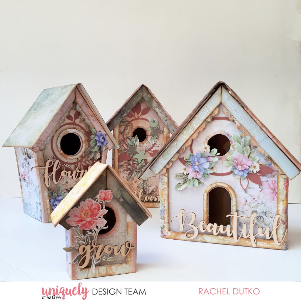 Decorative birdhouse kit sample by Rachel Dutko featuring elements from Uniquely Creative’s Botanical Chronicles and Floral Archives collections – includes four pastel birdhouses adorned with layered florals, paper embellishments, and nature-themed sentiments like “flourish,” “bloom,” “grow,” and “Beautiful.” A charming display of handcrafted artistry and mixed media design.