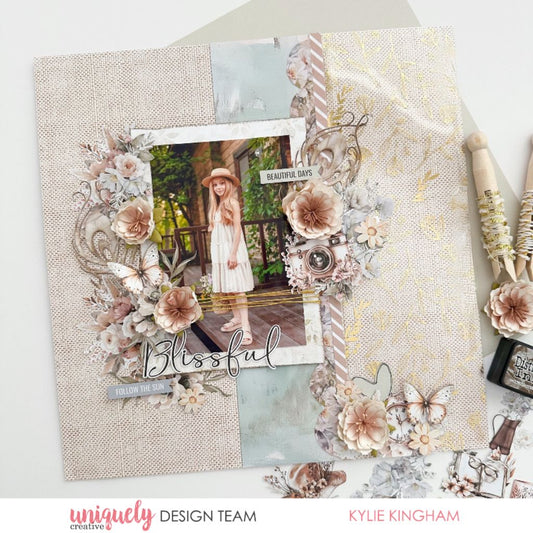 Scrapbook page by Kylie Kingham using Uniquely Creative Bohemian Escape collection – features a central photo framed by pastel florals, butterflies, vintage camera, and layered embellishments. Sentiments like “Blissful” and “Follow the Sun” enhance the soft, nature-inspired design perfect for documenting beautiful days.