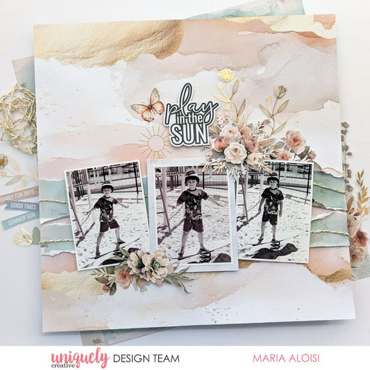 Summer-themed scrapbook page by Maria Aloisi using Uniquely Creative Bohemian Escape collection – features pastel watercolour background, gold accents, and black-and-white photos of a child playing in sand. Embellished with florals, butterflies, and sentiments like “play in the SUN” and “FAMILY FUN DAYS” for a joyful, sun-kissed memory.