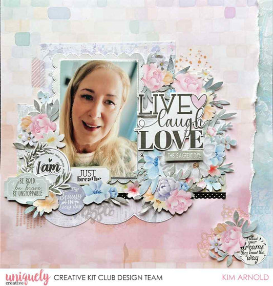 A scrapbook layout design featuring a layered paper collage from the Heart & Soul Collection with a central photo of a smiling blonde woman, surrounded by pastel pink, blue, and white floral elements, layered papers, and decorative text including 'LIVE laugh LOVE' and 'Just breathe'.