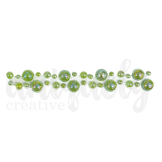 Close-up of sage green pearl tape showing graduated sizes of iridescent acrylic pearls arranged in decorative pattern on adhesive strip for card making and scrapbooking