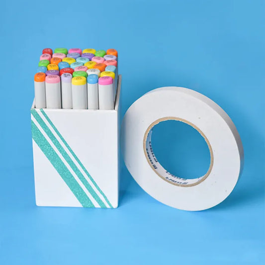 Box of colourful markers and a roll of white tape. The box has some lines across in various widths where they have used double sided tape to adhere some foil decoration.