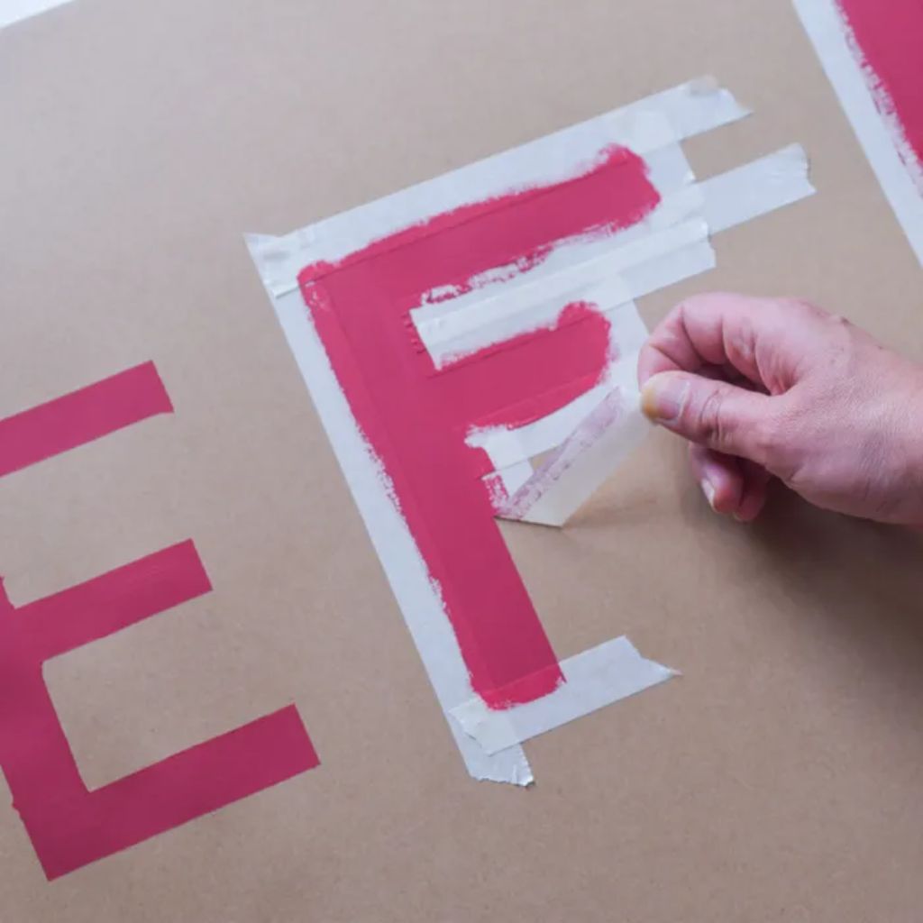 Hand removing masking tape after painting in the area that wasn't masked, giving a crisp, clear edge.
