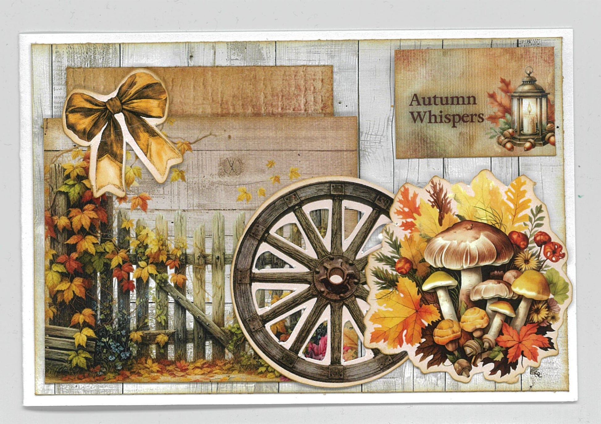 Autumn Whispers card sample 1 – landscape card with whitewashed timber background, golden bow, wagon wheel, autumn leaves and mushroom cluster die-cut embellishments