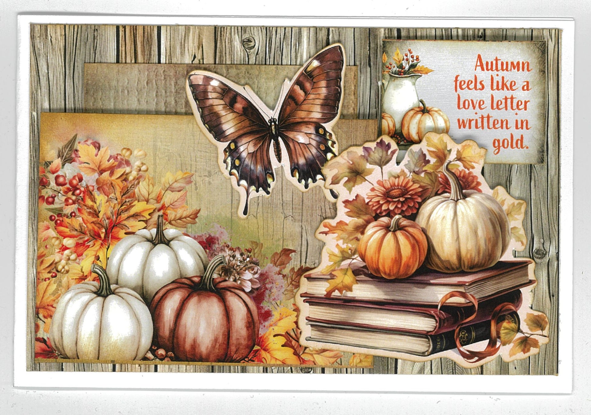 Autumn Whispers card sample 3 – landscape card with weathered timber background, large butterfly, white and rust pumpkins, autumn florals and stacked books die-cut embellishments with quote 'Autumn feels like a love letter written in gold'
