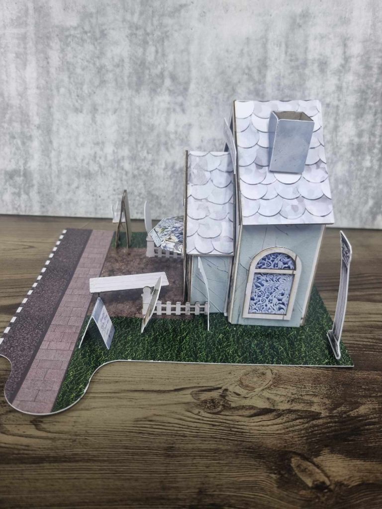 3Quarter Designs Enchanting Treasures Boutique Gift Shop miniature building right side view showing scalloped roof tiles, chimney, arched side window with blue floral detail, picket fence, pergola, and jigsaw base board with grass and cobblestone path