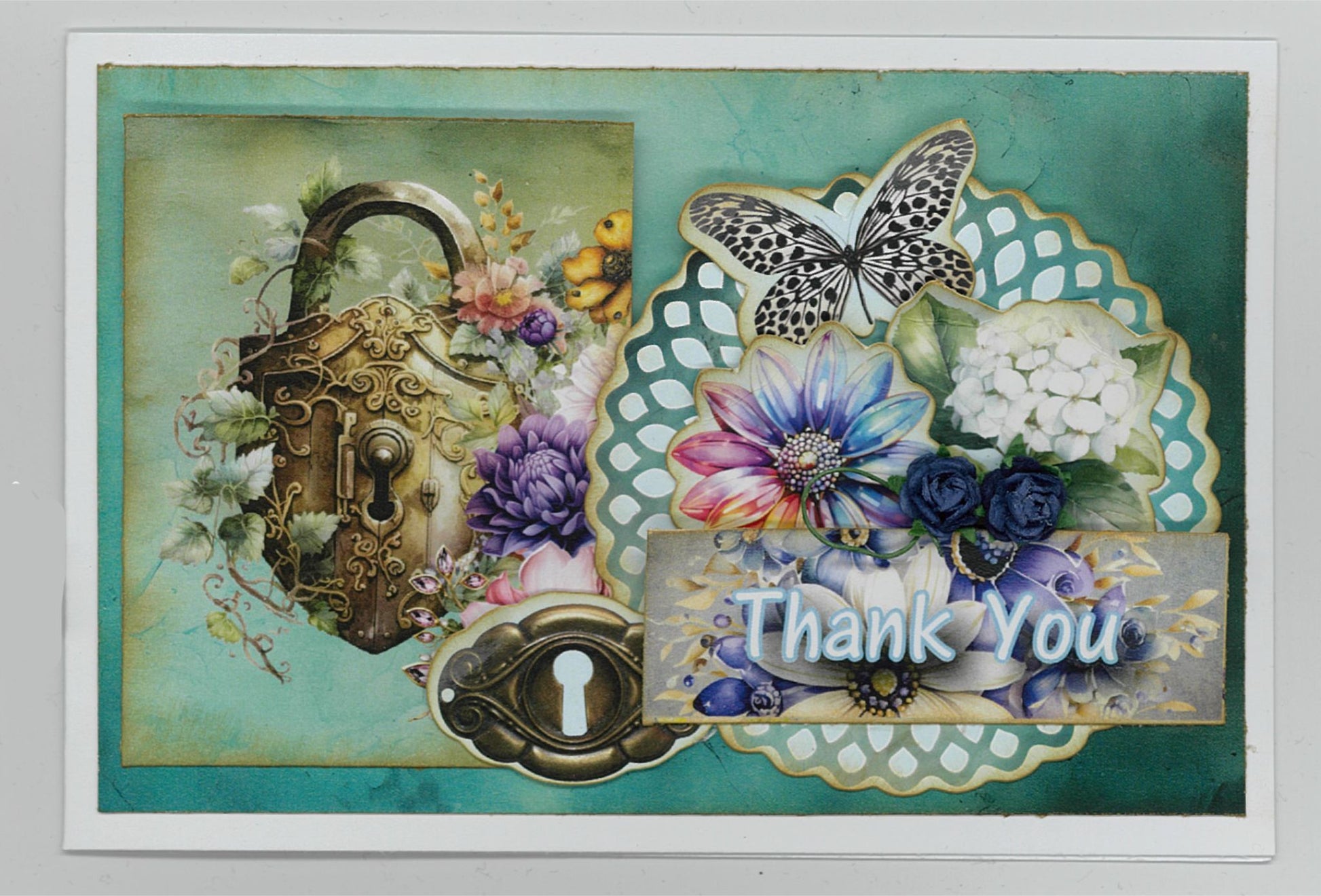 Handmade Thank You card using Floral Mechanica 6x4 Card Making Kit by 3Quarter Designs — landscape card featuring ornate steampunk heart padlock, keyhole, teal doily die-cut, black and white butterfly, and layered purple, blue, and pink florals on a teal distressed background 