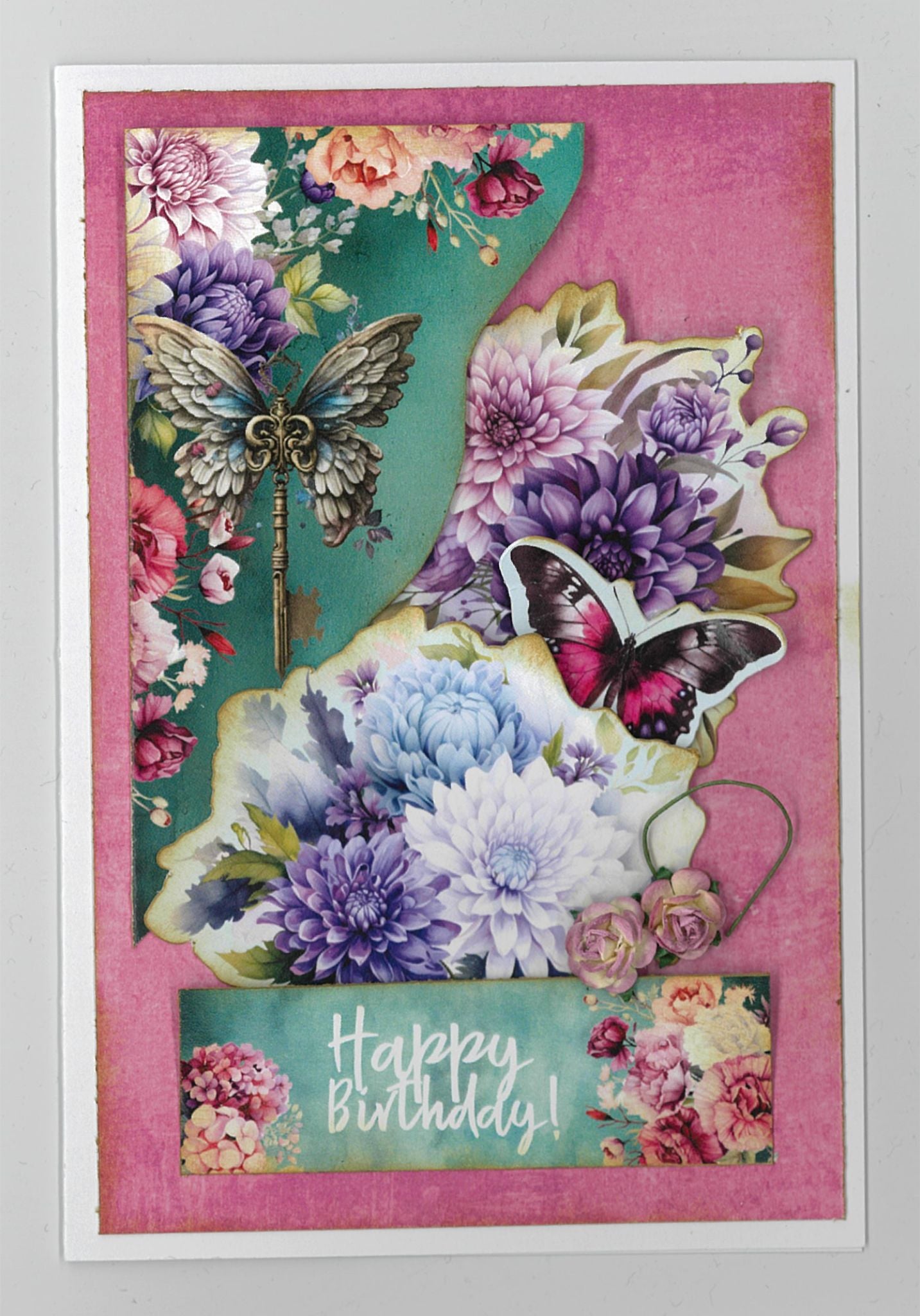 Floral Mechanica 6x4 Card Making Kit by 3Quarter Designs — portrait Happy Birthday card with winged key, pink butterfly, purple and white dahlias, and chrysanthemums on a pink and teal background 