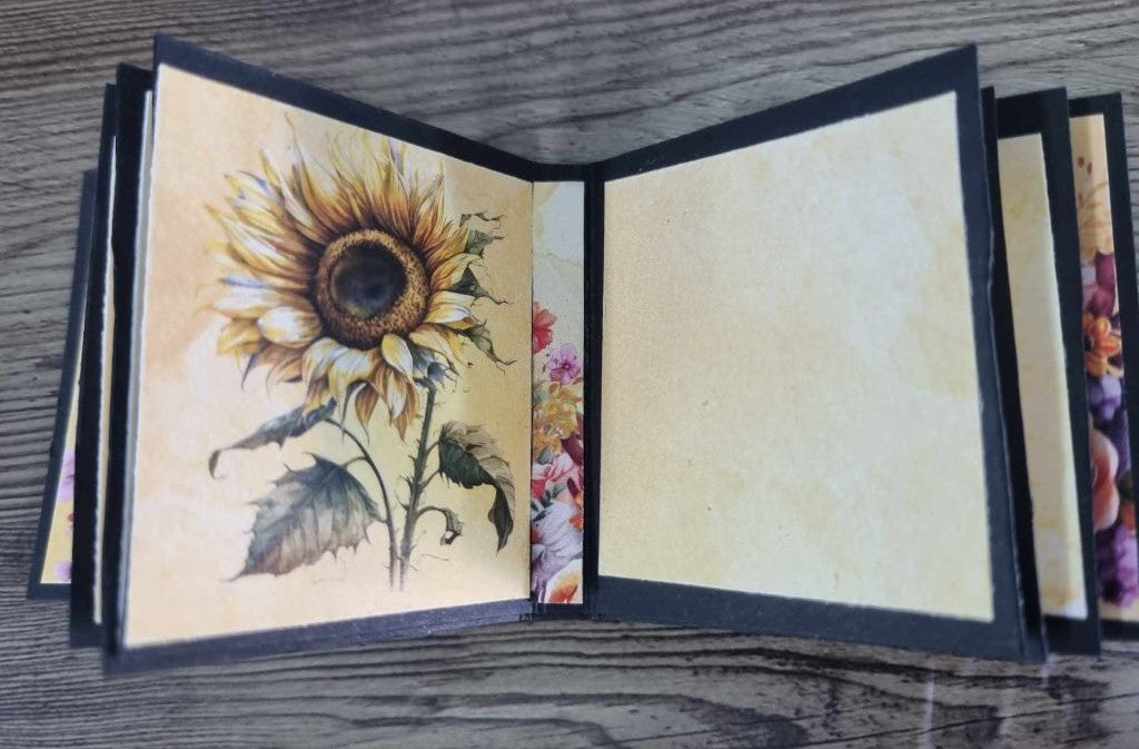 Mini album open to a spread — large botanical sunflower illustration on the left, plain cream journaling page on the right