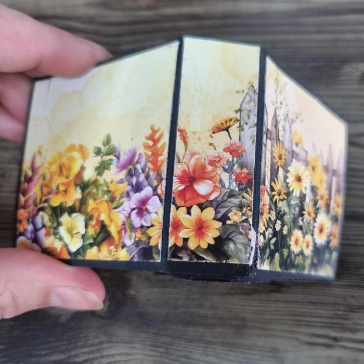 Mini album fanned open showing the spine with a continuous garden flower panorama across the covers