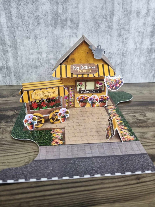 Front view of Hey Buttercup Florist showing the Picked Daily sign, hanging basket die-cuts, potted flower embellishments, and A-frame sandwich board
