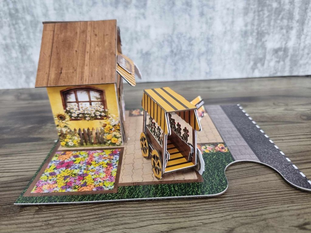 Side angle of Hey Buttercup Florist showing the sunflower wall mural, flower cart, and jigsaw-shaped base board with road section
