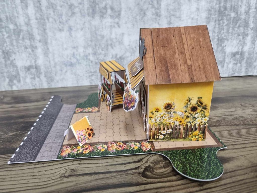 Side view of Hey Buttercup Florist showing the sunflower garden bed, picket fence, and entrance detail
