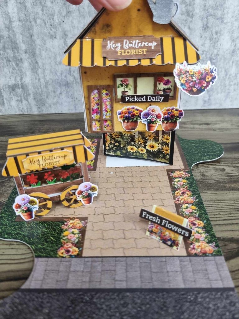 3Quarter Designs Hey Butter Cup Florist Kit assembled, shown being lifted to reveal a mini album inside. 