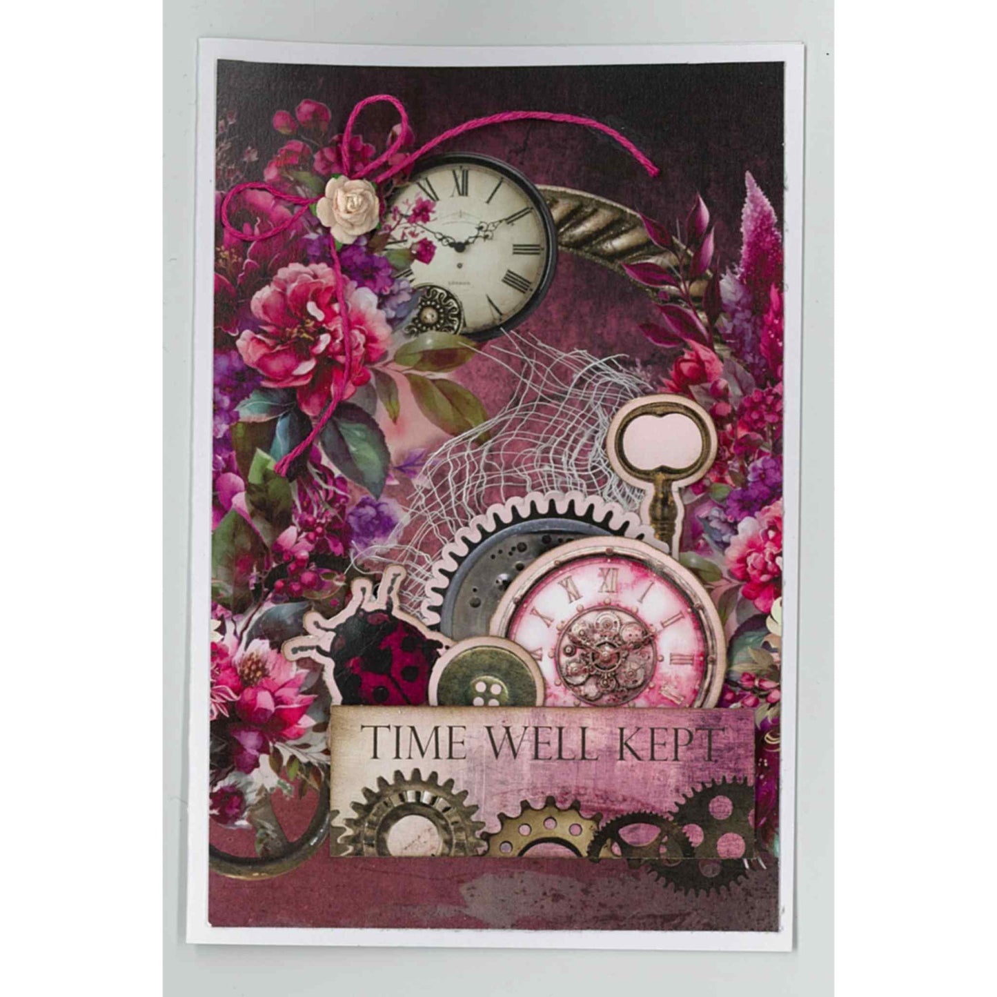 Handmade portrait card using Mrs Aeronaut kit with vintage clock face, cerise peonies, steampunk gears, lace and cerise bow, with Time Well Kept sentiment on deep plum floral background