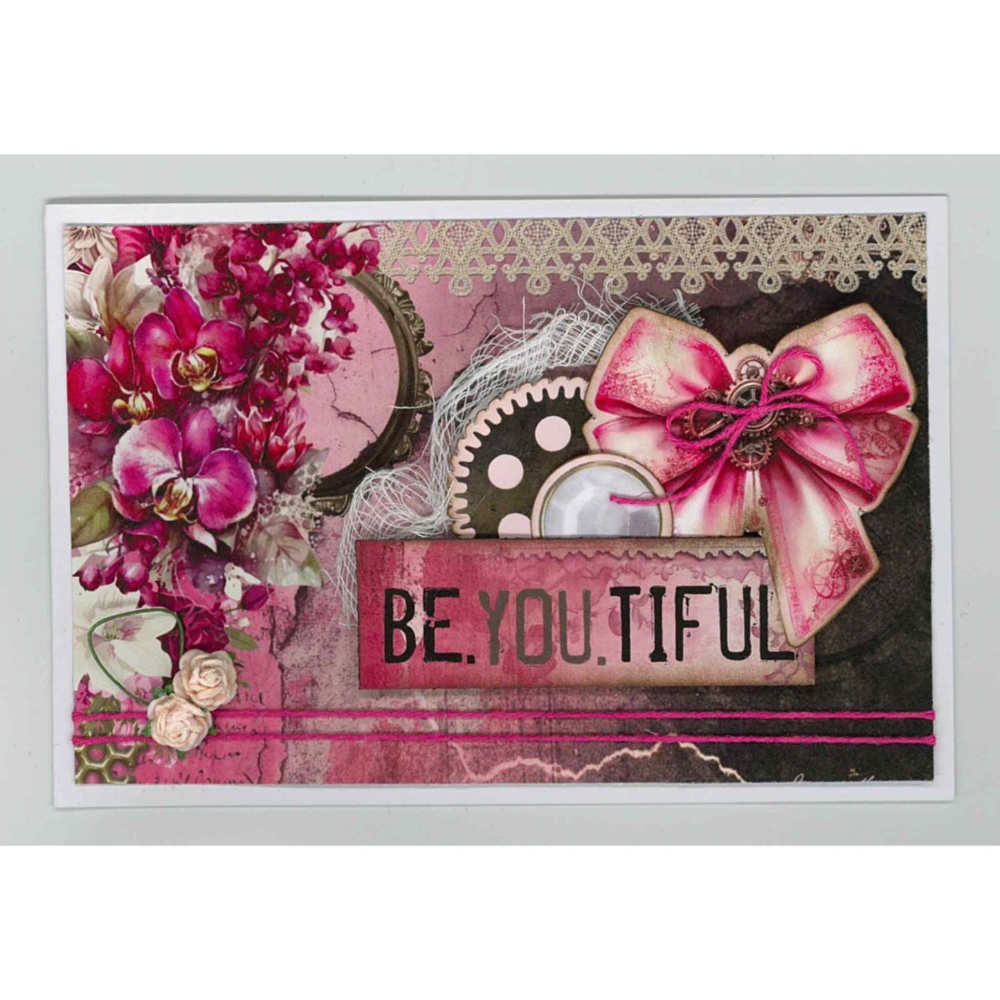 Handmade landscape card using Mrs Aeronaut kit with cerise orchids, steampunk gear, lace and cerise bow, with Be.You.Tiful sentiment on pink and dark mixed background with lace border