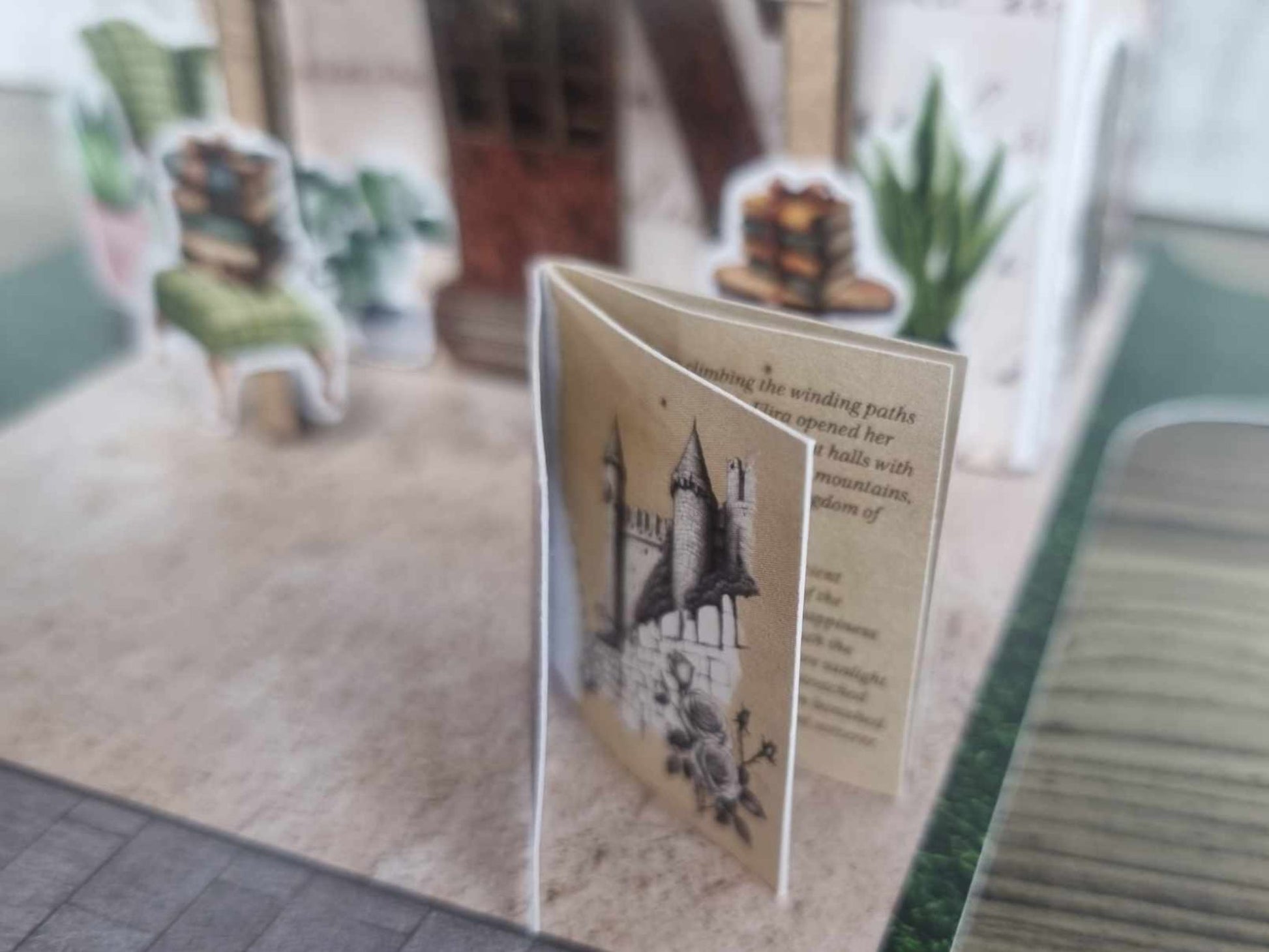 3Quarter Designs Once Upon a Time Book Shop mini album open showing an interior page with a fairy tale castle illustration and aged script journaling text, with green armchair and book die-cuts visible in the background