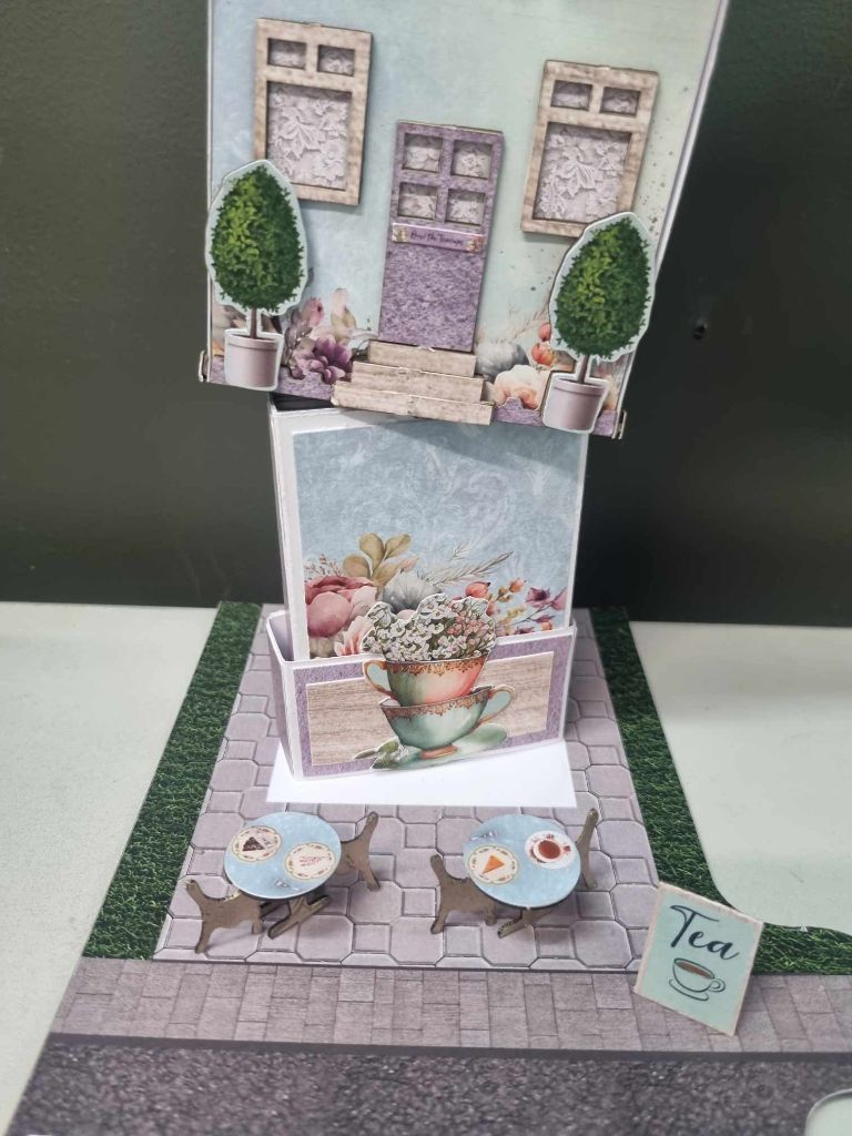 Mini album being placed inside the Over the Teacups Café, showing how the included A4 papers can be used
