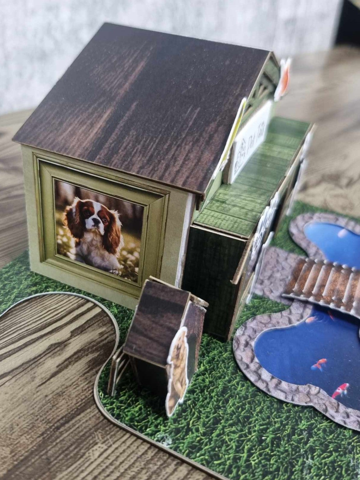 3Quarter Designs Pet Tails Pet Shop side view showing the photo frame window with a Cavalier King Charles Spaniel illustration and the bone-shaped pond with bridge