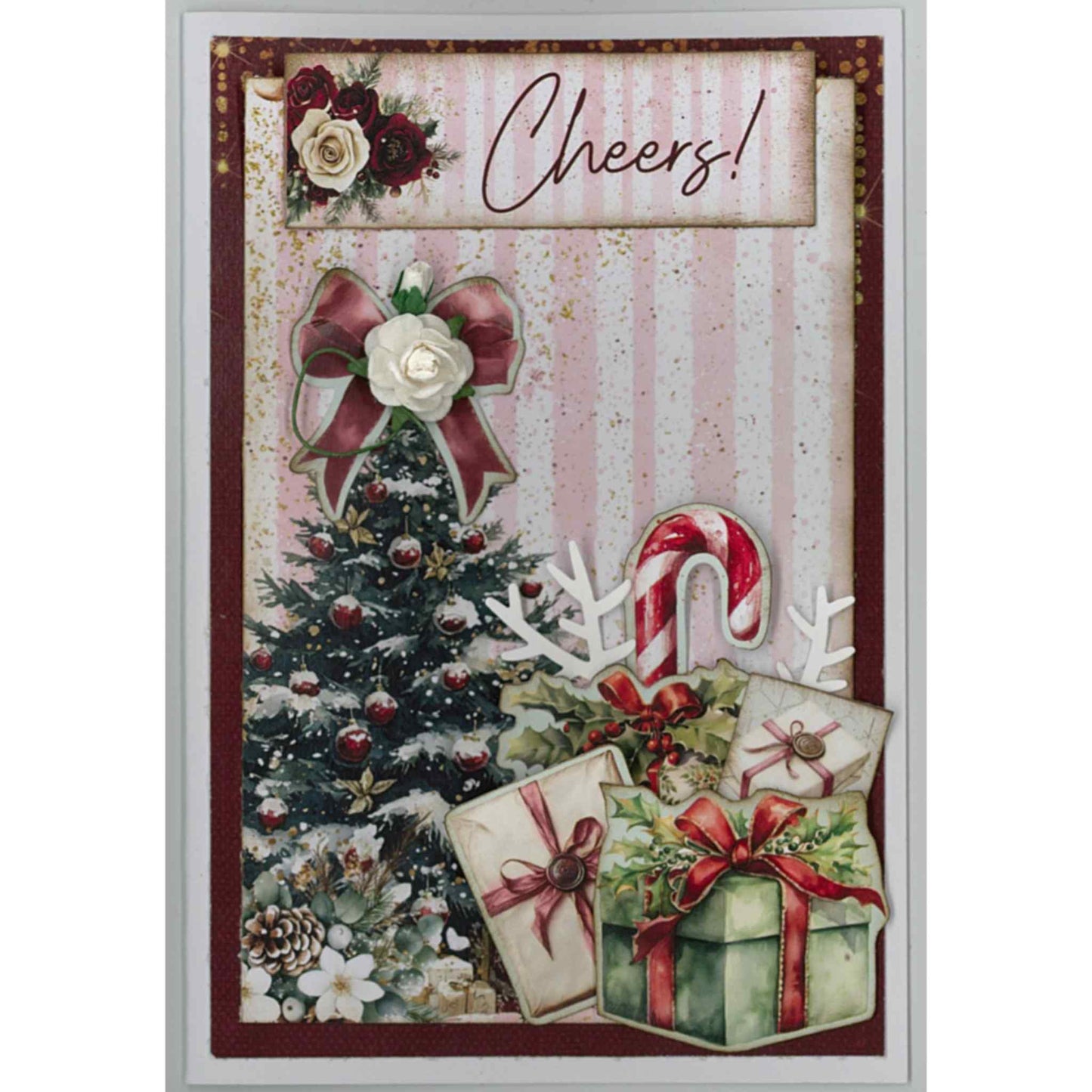 Handmade Silent Night Christmas card featuring snow-dusted Christmas tree with burgundy bow and white paper flower, candy cane, wrapped gifts, holly, pine cones and Cheers sentiment on pink stripe and burgundy background