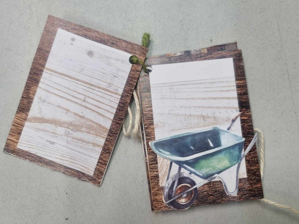 Sample mini album for The Toolbox open to a spread with a timber grain journaling page and a wheelbarrow illustration on a rustic wood background