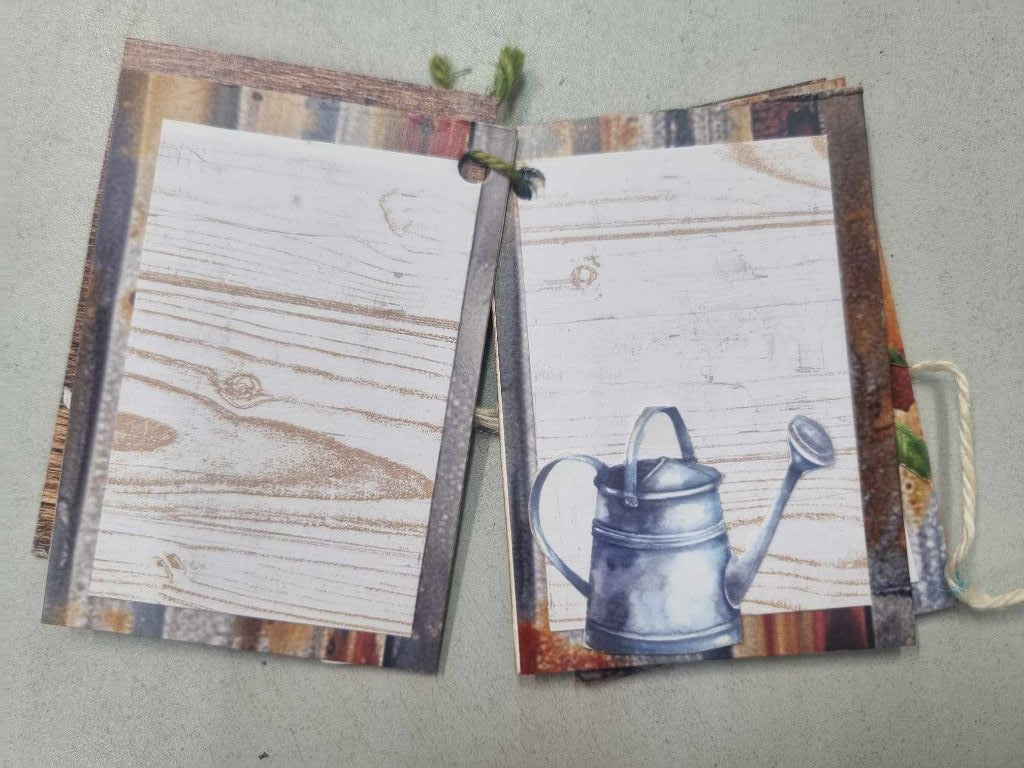 Sample mini album for The Toolbox open to a spread with a timber grain journaling page and a vintage watering can illustration
