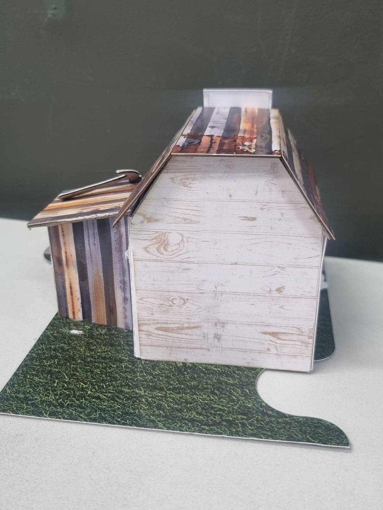 Side view of The Toolbox miniature building showing the corrugated iron roof detail and jigsaw-shaped base board