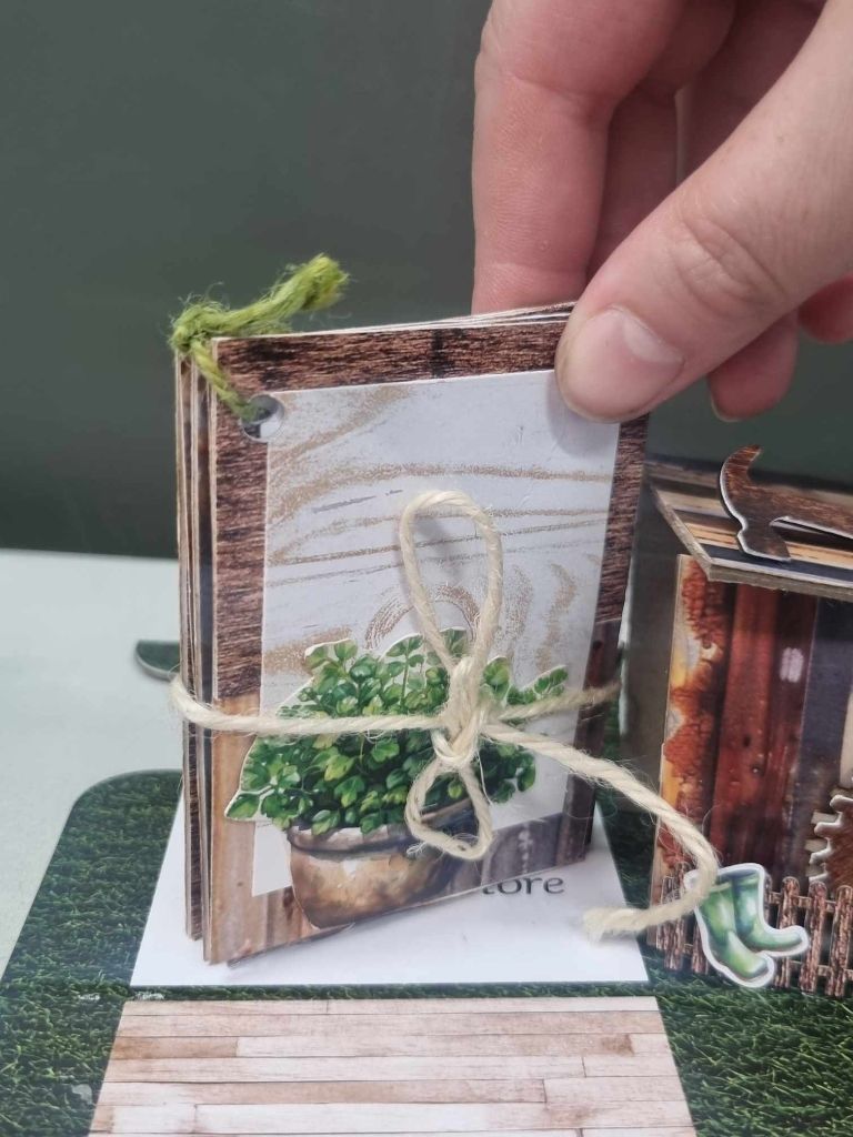 Sample mini album for The Toolbox kit, closed and tied with jute twine, featuring a rustic timber grain cover with a potted plant illustration