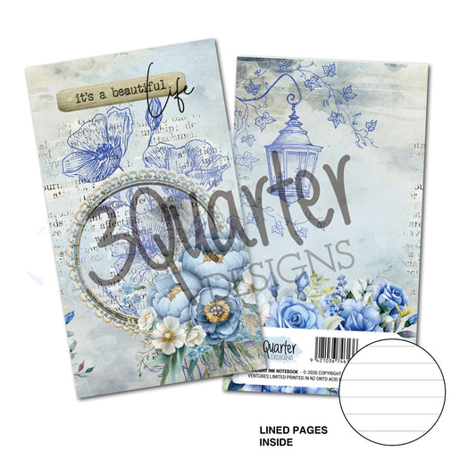 Twilight Ink Mini Notebook by 3Quarter Designs — front cover with "it's a beautiful life" sentiment, pearl oval frame, hand-drawn blue peonies and white florals on vintage script background; back cover with hand-drawn street lantern, trailing ivy, and blue rose bouquet on soft blue background; lined pages inside