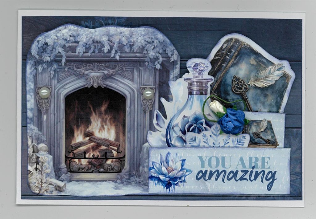 Winter scene with fireplace, books, blue florals, and “YOU ARE amazing” message on a handmade card