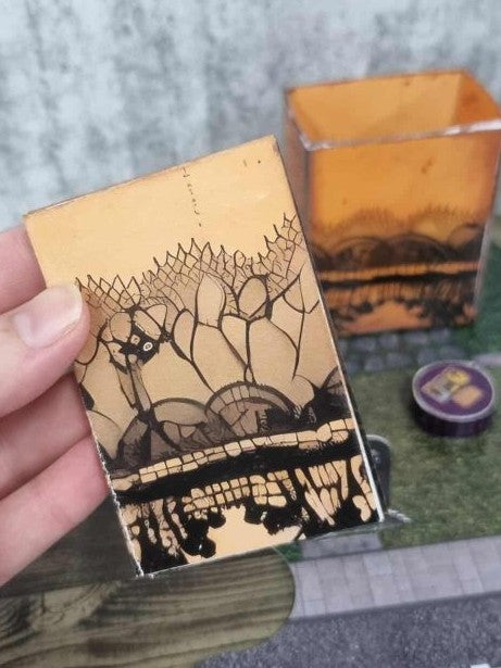 3Quarter Designs Witchwood Charm Tarot Store hidden star book showing the front cover decorated with a black silhouette, spider web lace, and gothic Halloween scene on an aged orange background, with the open star book box and purple crystal ball table visible in the background