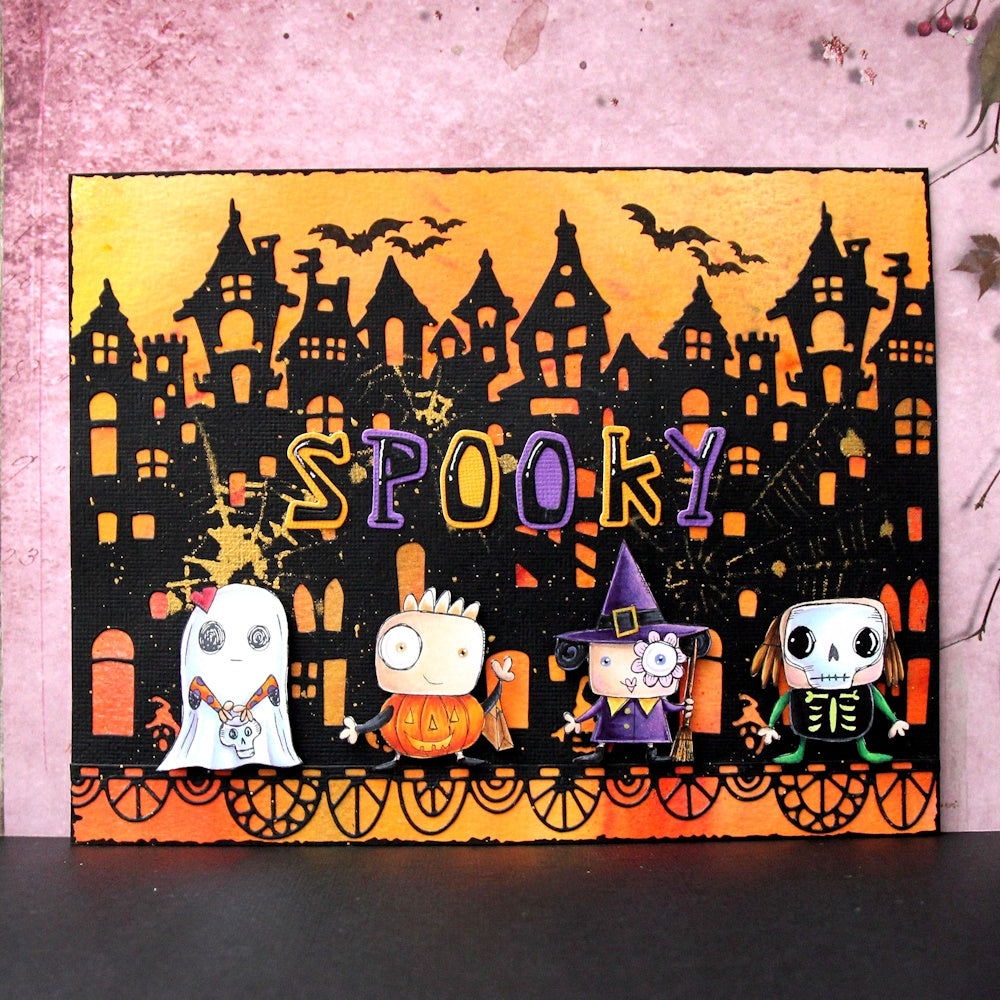 'SPOOKY' Halloween card made with AALL & Create Letter Soup dies featuring haunted house silhouette with orange sunset sky, cute ghost, pumpkin, witch, and skeleton characters with flying bats and decorative border