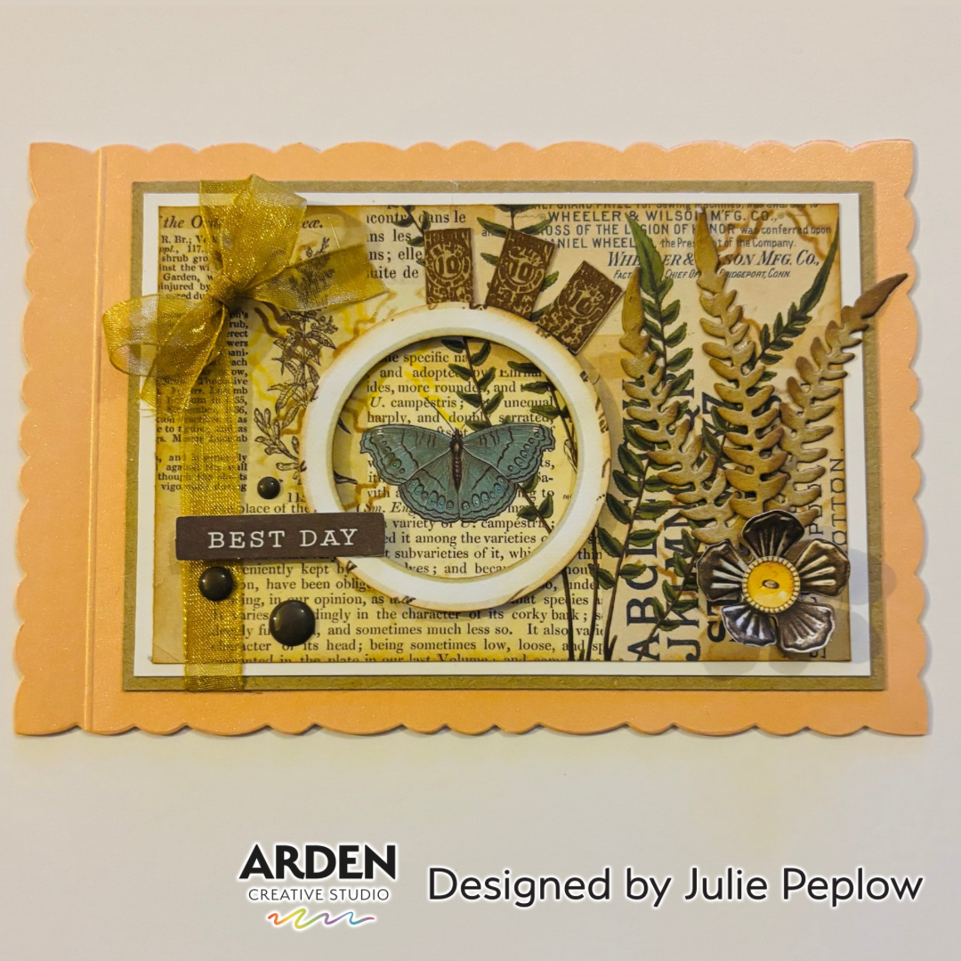 Handmade card sample using Arden Creative Studio Hidden Creek collection, featuring vintage newsprint patterned paper, die-cut fern leaves, butterfly focal point in a circle frame, gold ribbon bow, metal flower embellishment, and a "Best Day" sentiment.