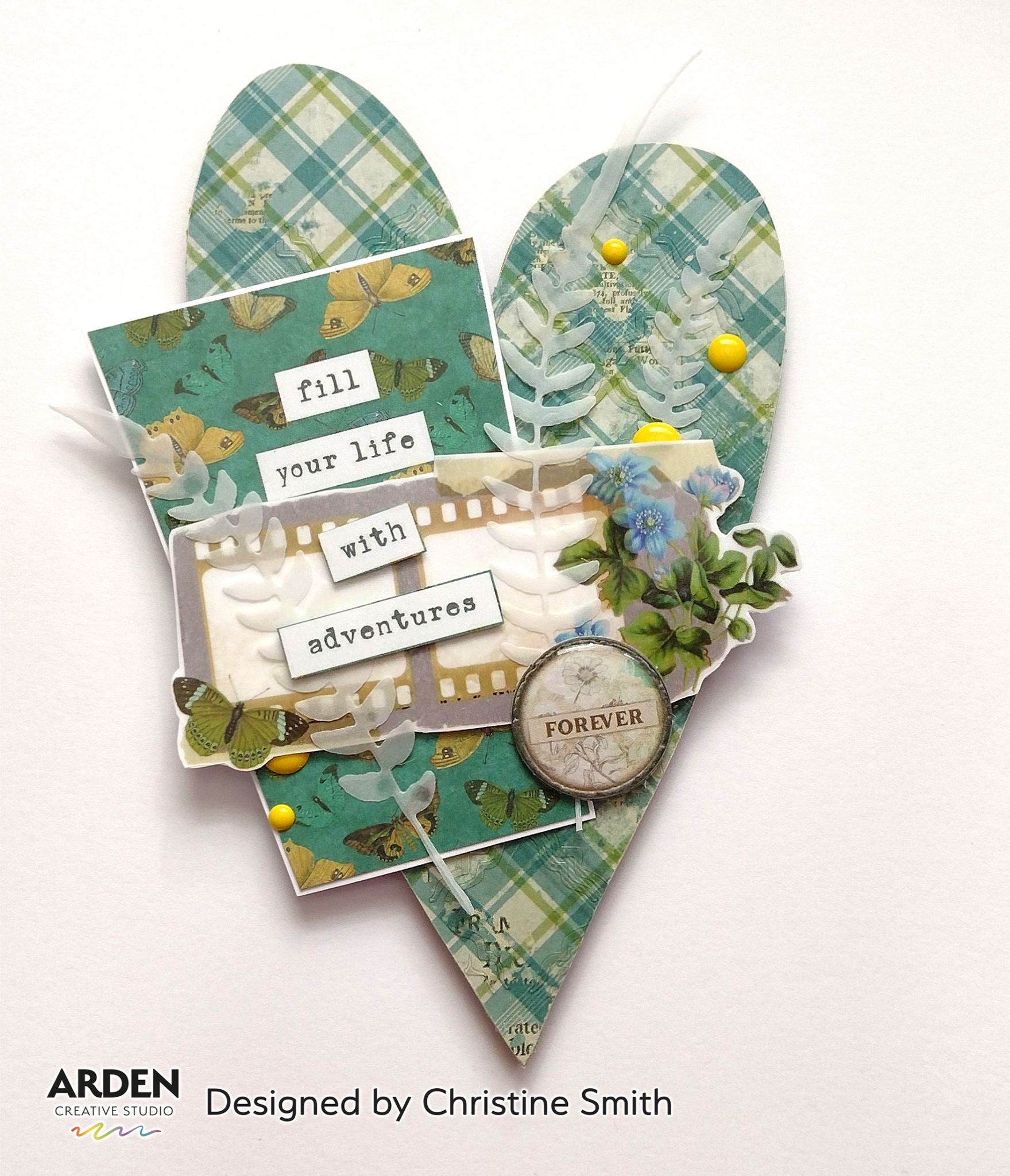 Handmade heart-shaped pocket card sample using Arden Creative Studio Hidden Creek collection, featuring teal plaid patterned paper, film strip PET Tape, vellum fern die-cuts, blue floral embellishments, yellow enamel dots, and a "Fill Your Life With Adventures" sentiment.