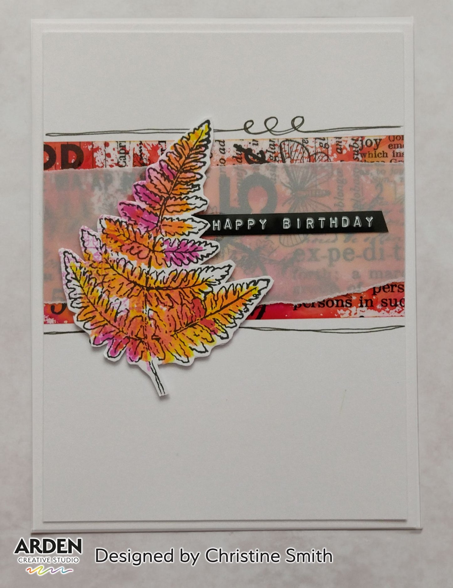 Handmade birthday card sample using Arden Creative Studio Hidden Creek collection, featuring a large fern stamp in warm autumn tones of orange, yellow and pink, layered over a mixed media collage background with vintage newsprint stamping and a bold "Happy Birthday" sentiment strip.