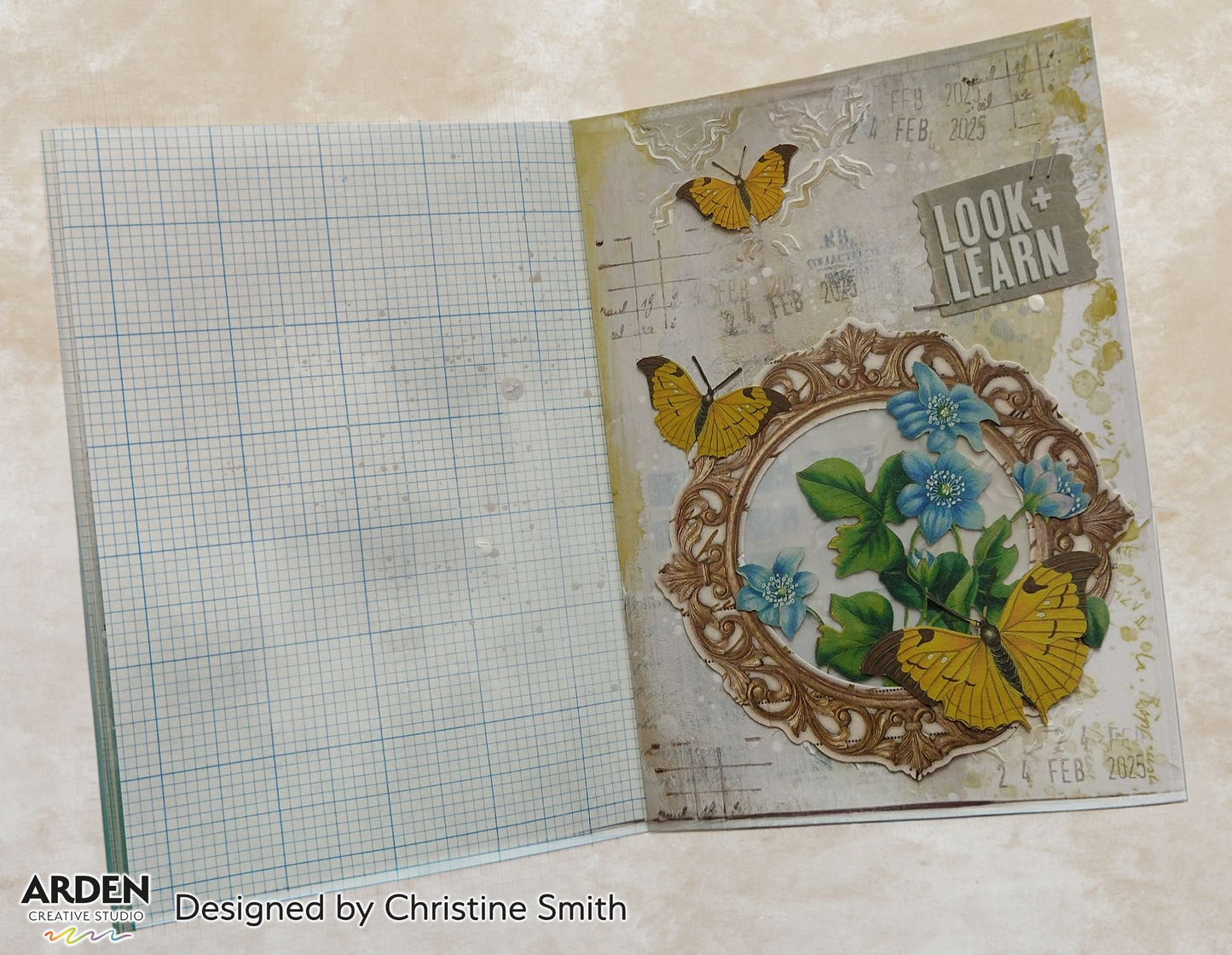 Handmade journal page sample using Arden Creative Studio Hidden Creek collection, featuring an ornate gold mirror frame die-cut with blue floral and leaf cluster focal point, yellow butterfly die-cuts, vintage script and graph paper background, mixed media ink splatters, and a "Look + Learn" sentiment tag.