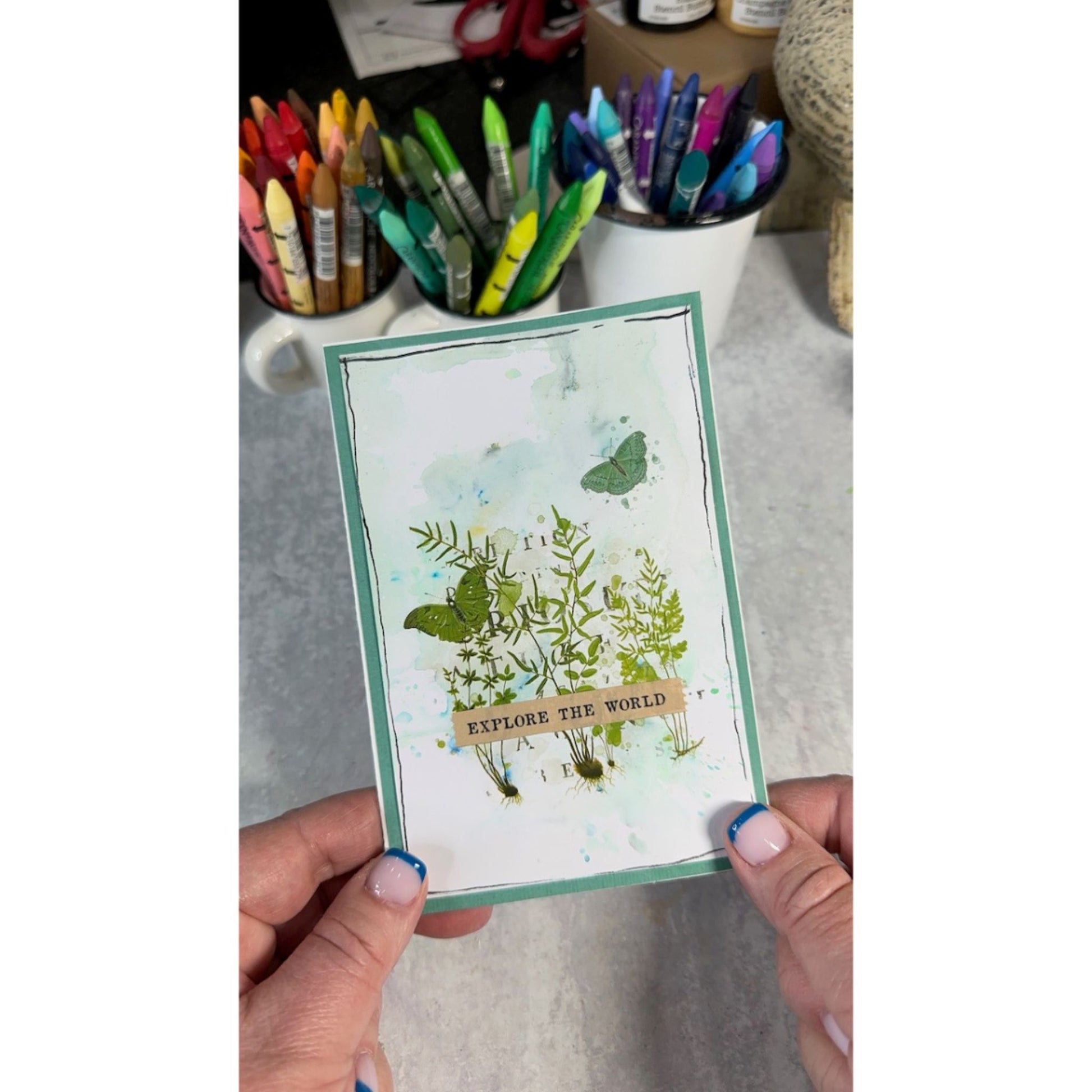"Explore the World" handmade card sample using Arden Creative Studio Hidden Creek collection, featuring botanical fern and wildflower stamping in olive green, teal butterfly stamp, and a soft watercolour ink wash background on a teal cardstock base.