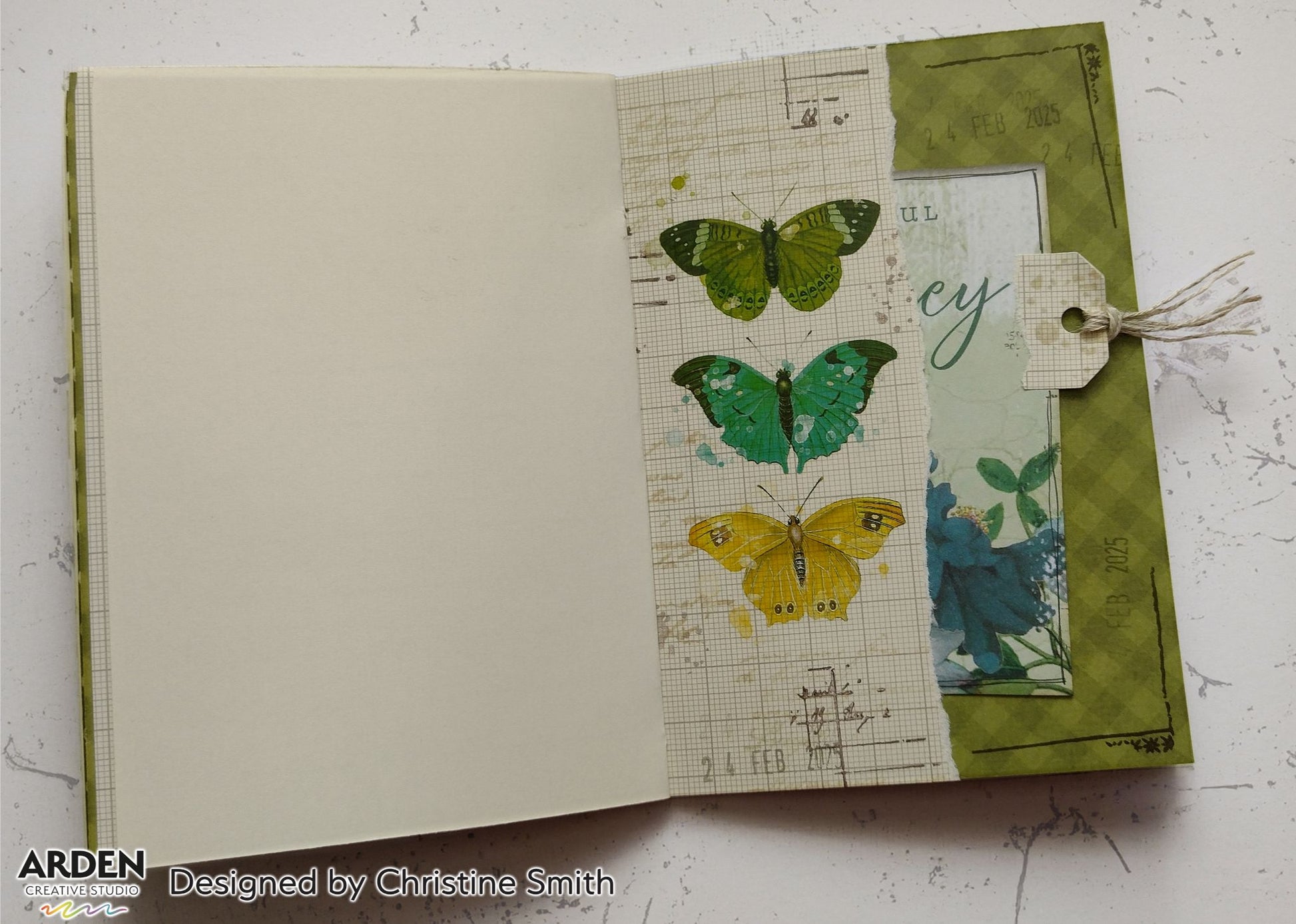 Open junk journal spread sample using Arden Creative Studio Hidden Creek collection, featuring three large butterfly stamps in green, teal and yellow on a vintage grid patterned paper background, with a teal botanical pocket and twine tag embellishment.