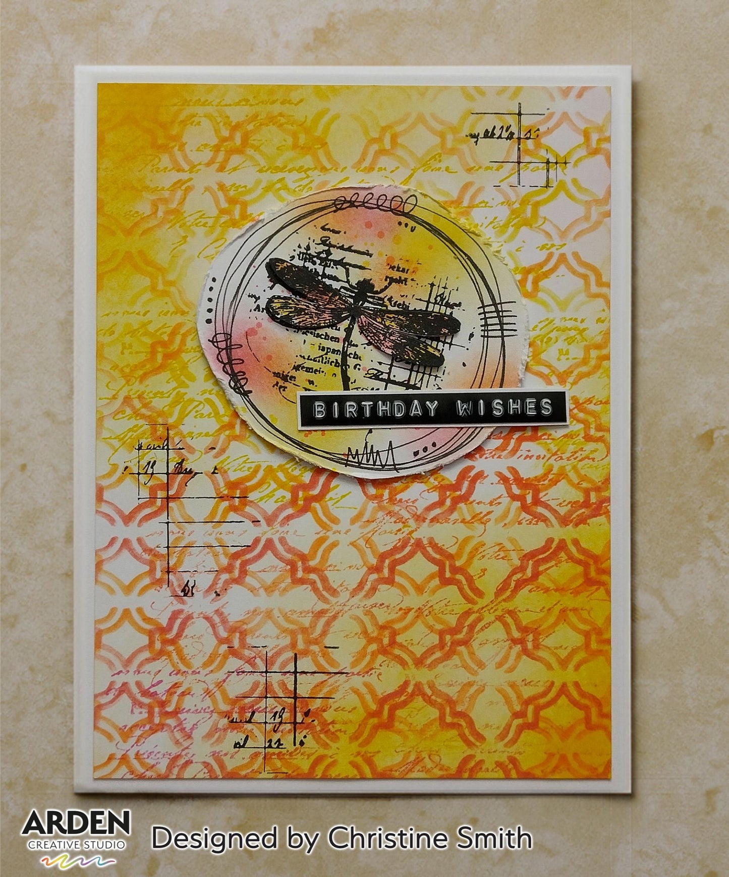 "Birthday Wishes" handmade card sample using Arden Creative Studio Hidden Creek collection, featuring a dragonfly stamp focal point in a circle frame, vintage script and Moroccan lattice stencilling, and a vibrant yellow and orange Distress Oxide ink blended background.