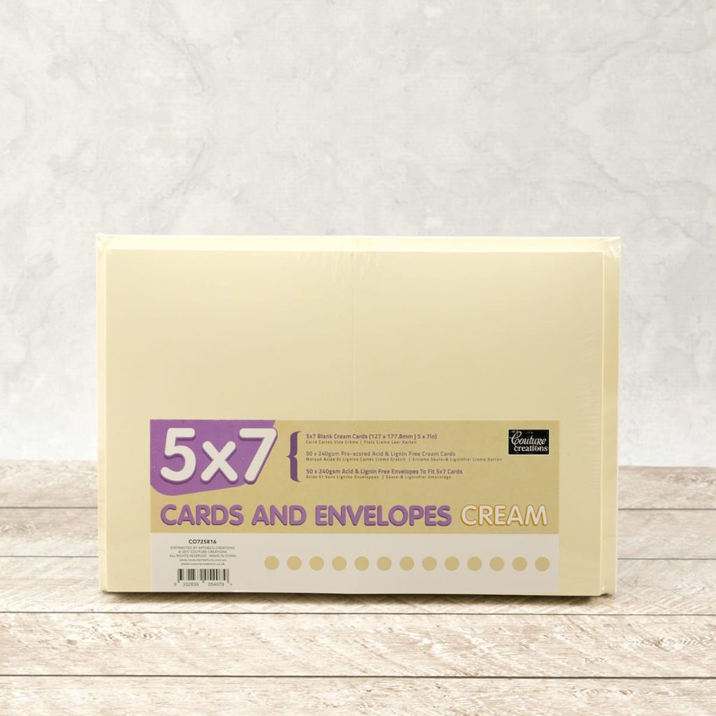 Packet of 5x7" cream cards and envelopes on a wooden surface with a light grey background