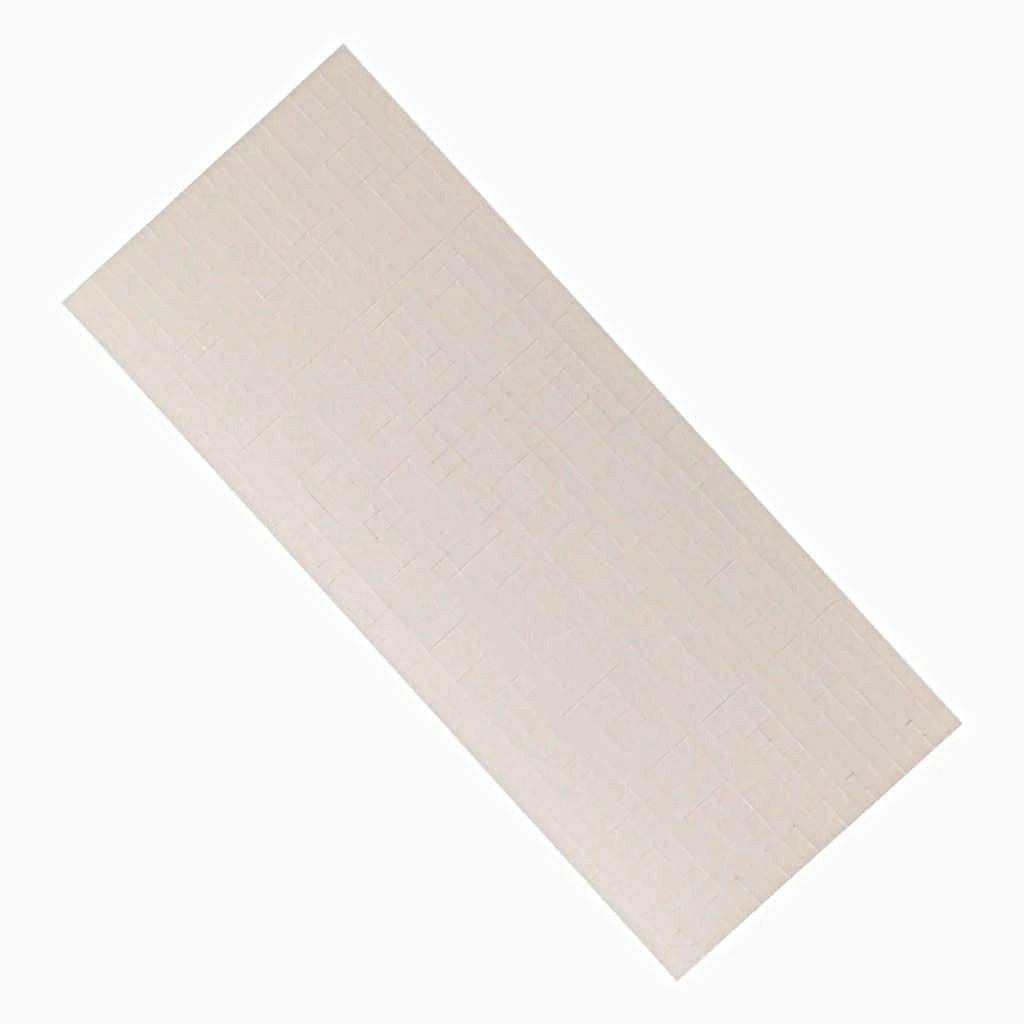 Sheet of white adhesive foam squares on a white background. 