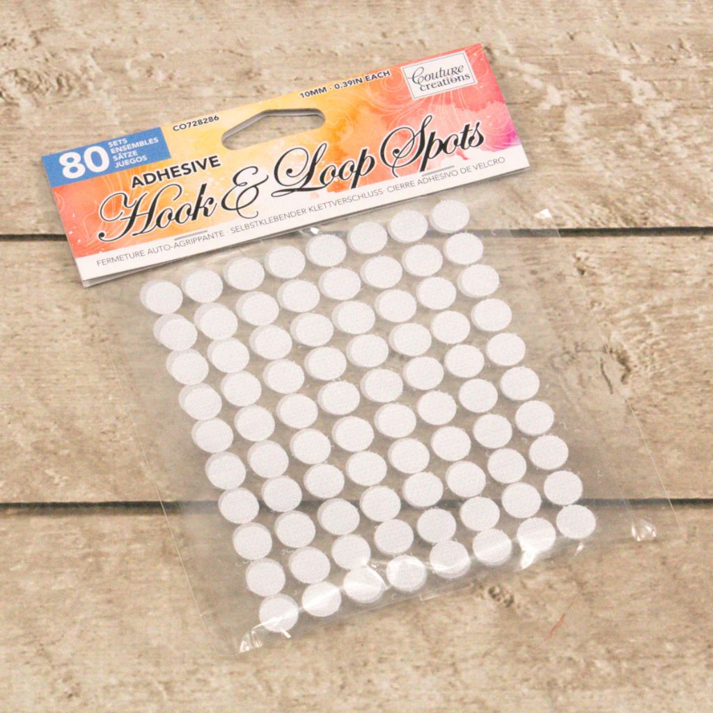 Pack of adhesive hook and loop spots with packaging on a wooden surface
