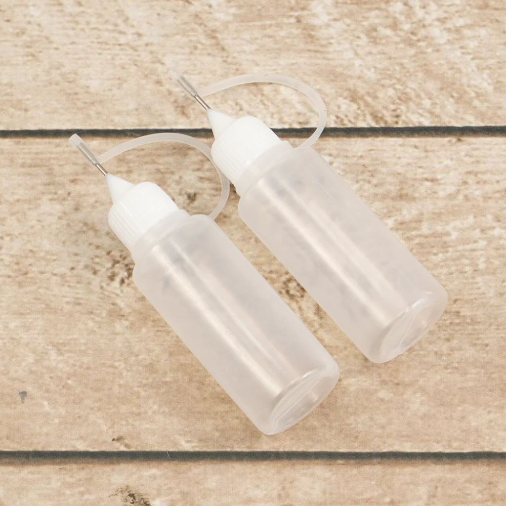 Two clear, empty, plastic bottles with nozzles on a wooden surface