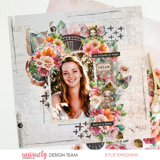 Scrapbook layout using Uniquely Creative Dressed in Daydreams collection featuring layered watercolour flowers in pink and orange, vintage clock ephemera, lace doily, 'she believed in magic' and 'Dream' sentiments on distressed background