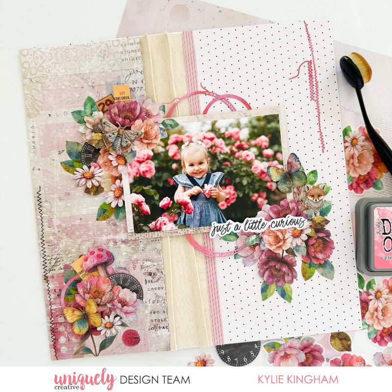 Mixed media scrapbook page with Uniquely Creative Dressed in Daydreams papers featuring watercolour butterfly, pink florals, vintage mushroom embellishment, polka dot background and 'just a little curious' sentiment