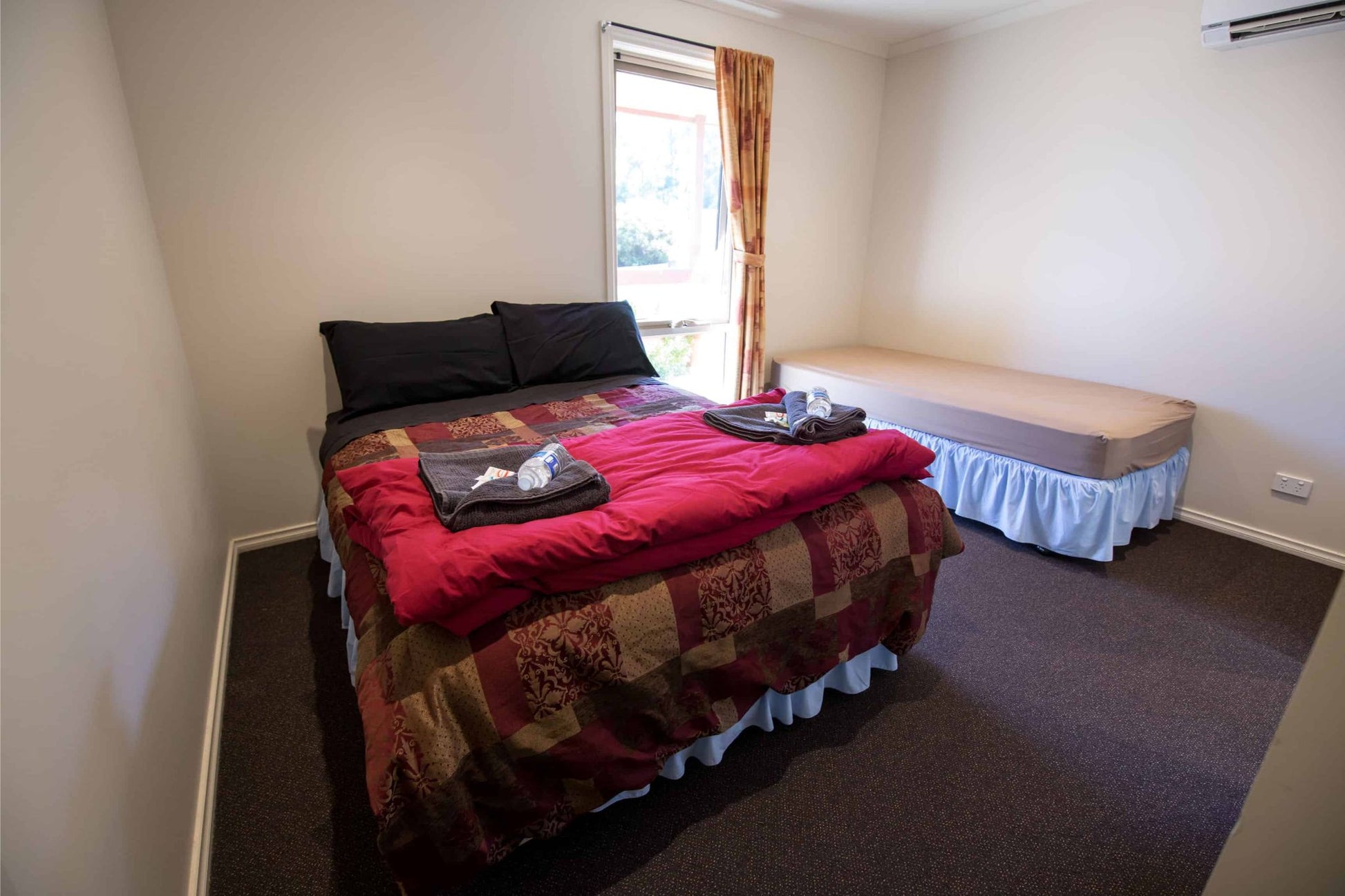 Comfortable bedroom with double bed and single beds at Handmade Craftery Retreat accommodation in Yarra Ranges